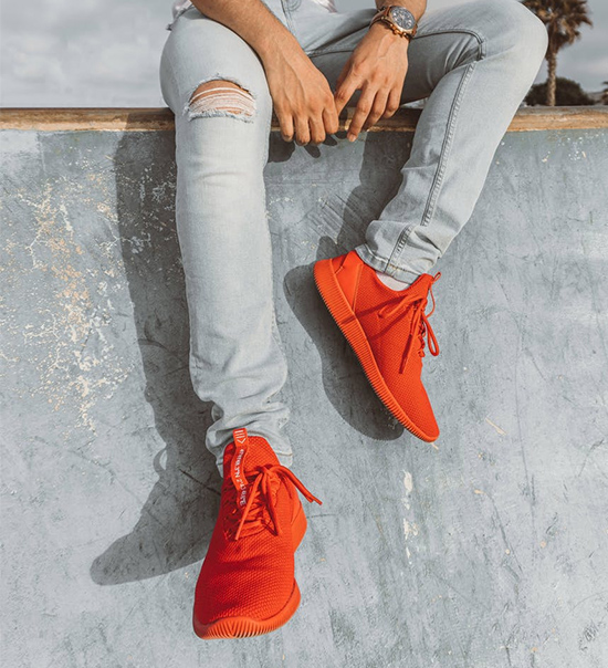 a man's legs with bright orange shoes